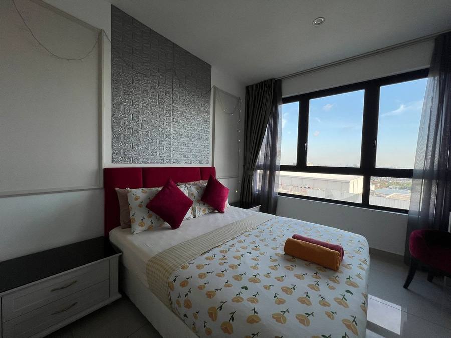 Bedroom with a queen bed dressed in patterned linen, beside a corner window looking over Shah Alam.