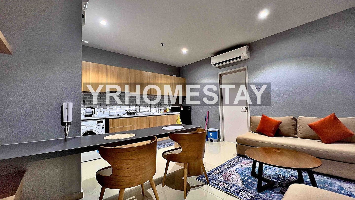 The living area of the Liberty Tower apartment at i-City, with a sofa, dining table and the kitchen beyond.
